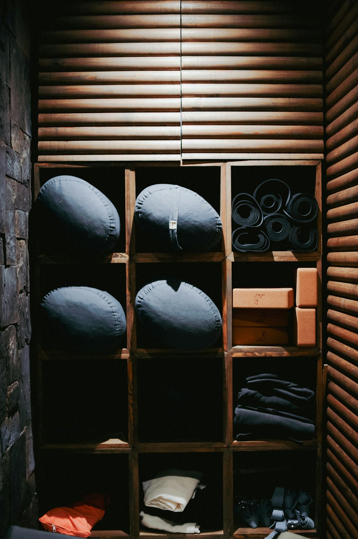 A neatly organized storage shelf with yoga and wellness equipment in a cozy interior.