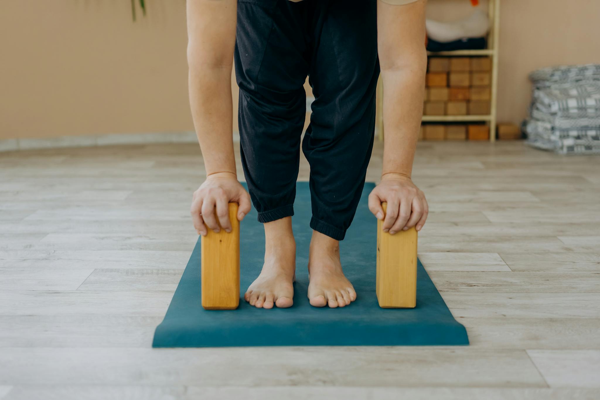 A person practicing yoga using blocks on a mat indoors, focusing on balance.